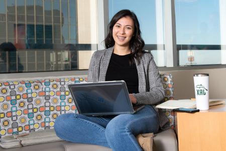 Student seating at a study room with laptop in hand.